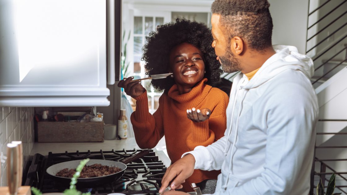 A woman getting a man to taste food