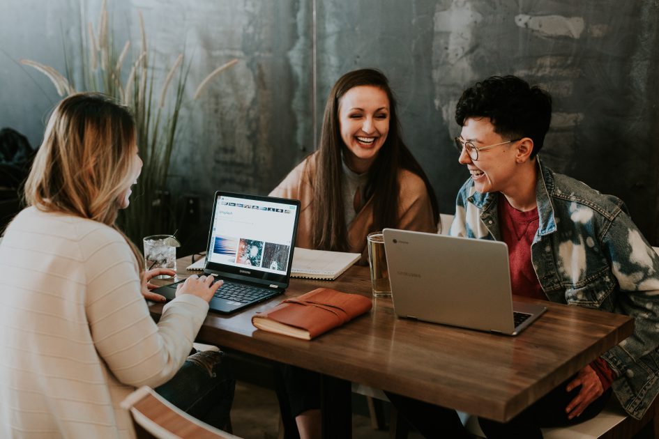 Group of people laughing with laptops 