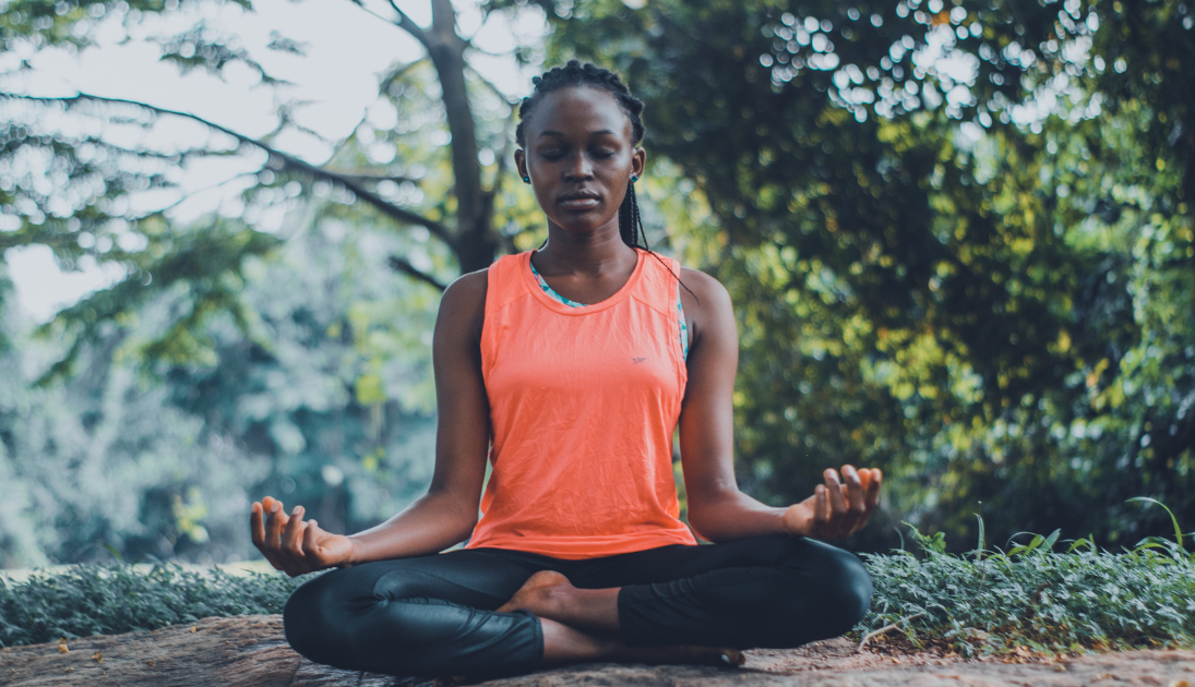 Woman practicing wellness by meditating outdoors